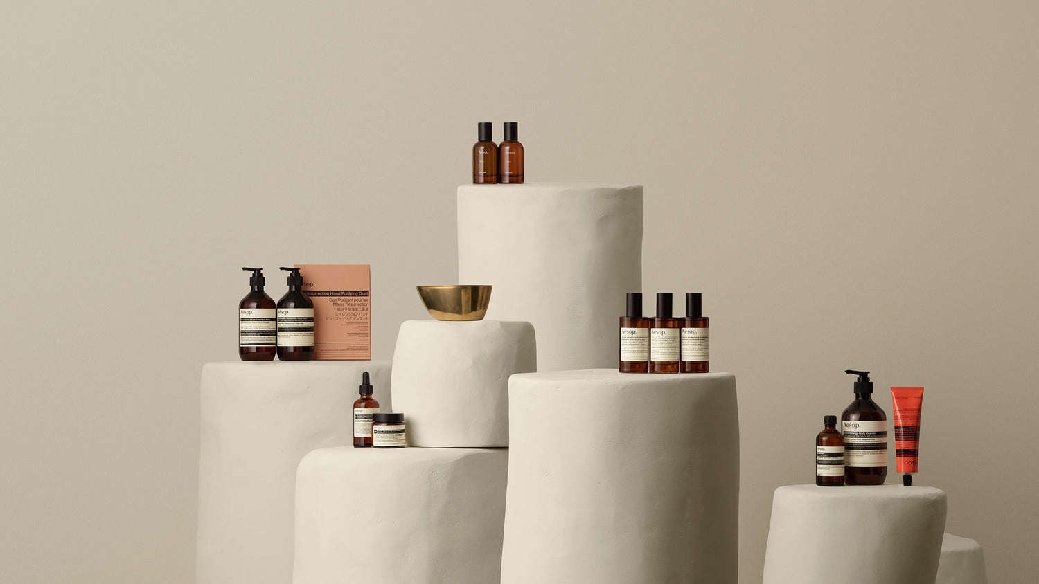 Assorted Aesop products placed on white, stone pillars of various sizes
