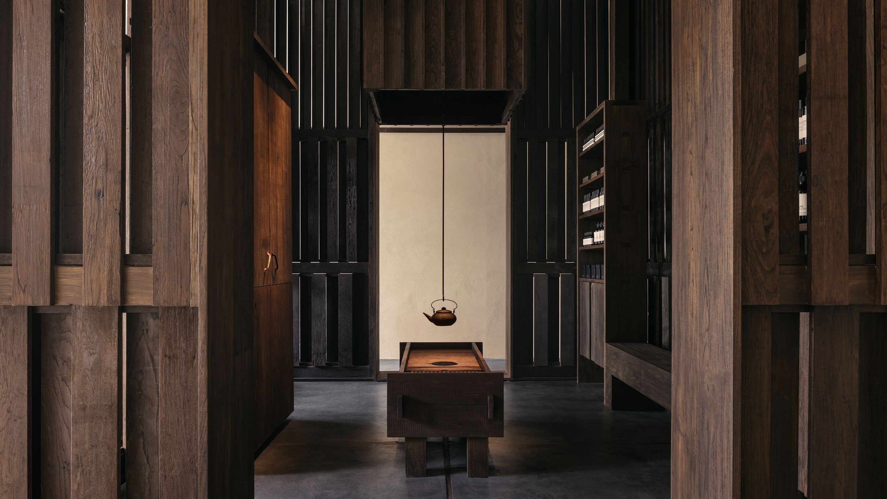 The Aesop Thonglor store interior with reclaimed teak wall panelling and a suspended steel teapot.